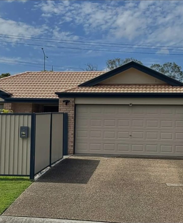 Single storey Toowoomba home with a tan repainted garage door, terracotta tiled roof and navy fascia and gable trim